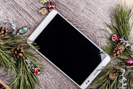 Tablet pc with blank screen and christmas fir tree with cones and christmas tree decoration on a...