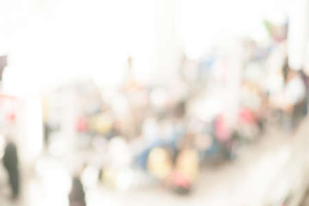 Blurred photo of an airport terminal with unrecognizible passengers passing by with luggage. Blurred background for topics of travel and transportation.の写真素材
