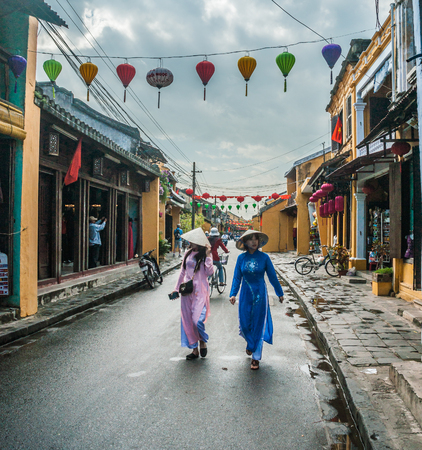 HOI AN, VIET NAM - FEBRUARY 4, 2015: Two unidentified asian female tourists in historical vietnamese clothes walk on a street in Hoi Ah on Feb 4, 2015. Hoi An is recognized as a World Heritage Site by UNESCO.のeditorial素材