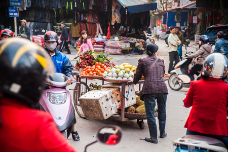 NINH BINH, VIETNAM - JANUARY 23, 2015: A woman in traditional conical hat sells vegetables and fruits in a movable vehicle. Exotic food is one of the main attraction for tourists in Vietnam.のeditorial素材