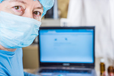 A female doctor is looking at a x-ray, computer is visible in the backgroundの写真素材