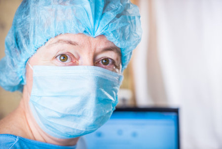 Female doctor wearing medical mask and surgical cap looking seriously and worried at patient with...