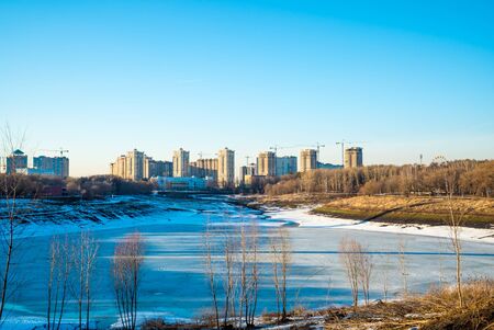 Residential buildings in winter with snow, park and city skyline with skyscrapers, blue sky.の写真素材
