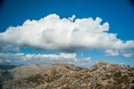 Beautiful landscape with rocky mountains and clouds on the western part of Mallorca island, Spain.  Tramuntana mountains with green bushes. Tourist trekking destination in Spain.の写真素材