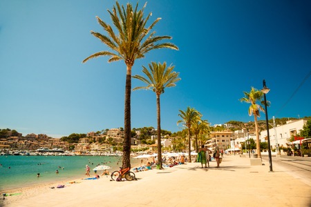 View of the beach of Port de Soller with people lying on sand and the old buildings visible in background, Soller, Balearic islands, Spain.の写真素材
