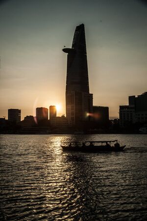Panorama of Ho Chi Minh viewed over Saigon river. Breathtaking dramatic light of sunset is highlighted by lens flare effect created by vintage photo equipment.の写真素材