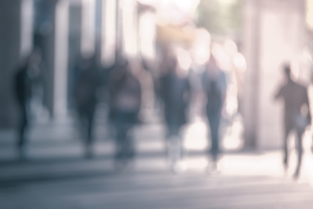 People walking down the street in the evening, beautiful light at sunset. The photo is purposely made out of focus, no faces are recognisibleの写真素材