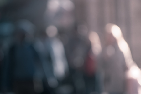 People walking down the street in the evening, beautiful light at sunset. The photo is purposely made out of focus, no faces are recognisibleの写真素材