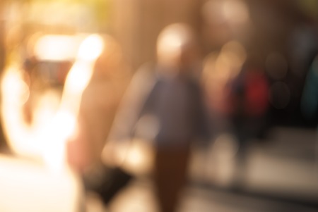 People walking down the street in the evening, beautiful light at sunset. The photo is purposely made out of focus, no faces are recognisibleの写真素材