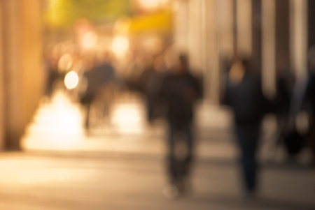 People walking down the street in the evening, beautiful light at sunset. The photo is purposely made out of focus, no faces are recognisibleの写真素材