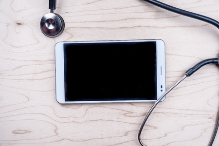 Tablet pc with medical objects on a desk as a metaphor for electronic diagnostic or healthcare mobile apps. Medical backgroundの写真素材