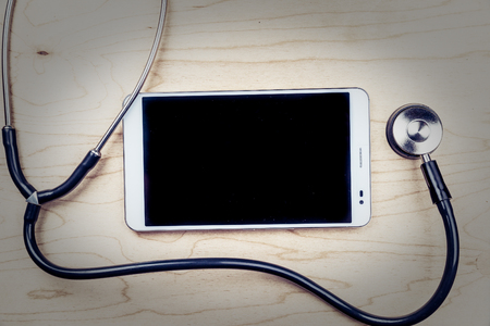 Tablet pc with medical objects on a desk as a metaphor for electronic diagnostic or healthcare mobile apps. Medical backgroundの写真素材