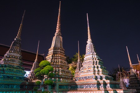 The beautifully decorated pagodas of Wat Pho temple at night. Bangkok, Thailand. Traditional religious architecture of Asia.の写真素材