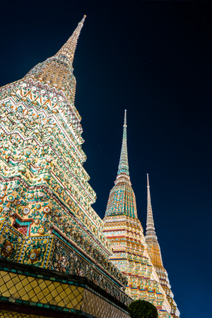 The beautifully decorated pagodas of Wat Pho temple at night. Bangkok, Thailand. Traditional religious architecture of Asia.の写真素材