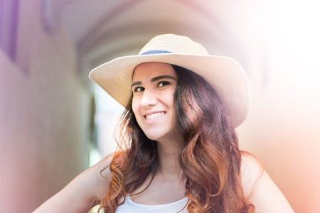 Girl with hat on summer day in the street.の写真素材