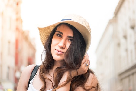 Girl with hat on summer day in the street.の写真素材