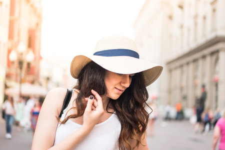 Girl with hat on summer day in the street.の写真素材