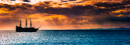A lone ship against the morning sky. A distant historic ship in dramatic atmosphere.の写真素材