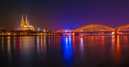 Sunset sky with colors and clouds over the city skyline Cologne with Bridge and Koeln Dom, Evening scene over Cologne Koln city with Kolner Dom Cathedral behind the Hohenzollern bridge.の写真素材