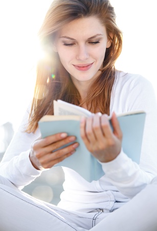 Delightful young woman reading a bookの写真素材