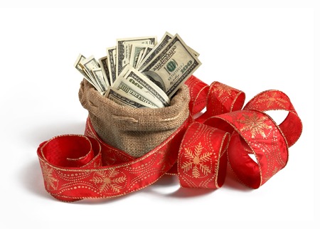 Bag of money - studio photography of bag full of hundred dollar bills, decorated with red Christmas ribbonの写真素材
