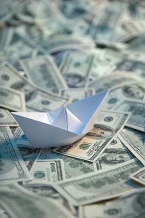 Origami paper ship at sea of money - studio photography of american moneys of hundred dollar on backgroundの写真素材