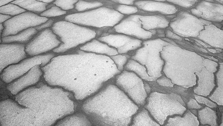 Dark asphalt road with cracks - outdoors photography of damaged asphalt driveway