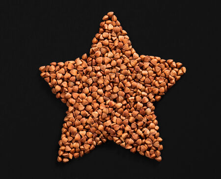 Star shape made of premium buckwheat groats on black backgroundの写真素材