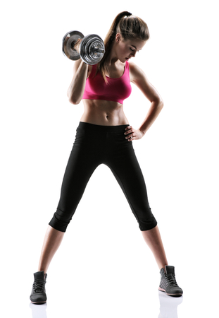 sporty muscular female brunette girl wearing sports clothes working out with dumbbells over white backgroundの写真素材