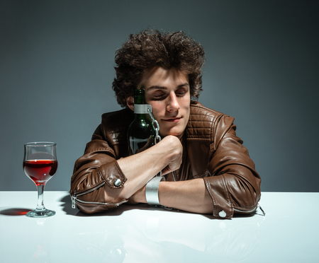 Young man is hugging a bottle of wine  photo of youth addicted to alcohol, alcoholism concept, social problemの写真素材
