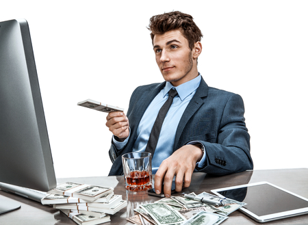 Young manager sitting at desk in office and thinking about his investment plan / photo of businessman addicted to alcohol at the workplace, mortgage and investment conceptの写真素材
