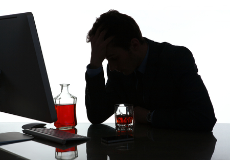 Silhouette of alcoholic drunk young man  photo of businessman addicted to alcohol at the workplace, depression and crisis conceptの写真素材