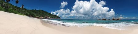 Tropical sandy beach with clouds and blue sky at summer sunny day, panorama outdoors photography of picturesque Seychelle islandsの写真素材