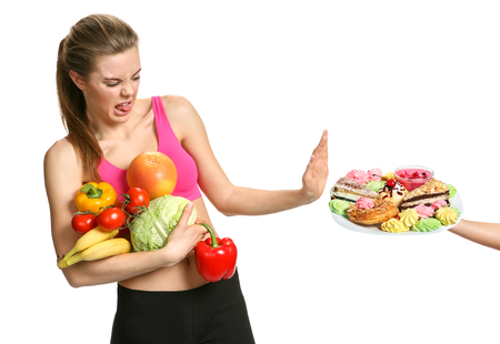 Beautiful girl on a white background chooses fruits and trying to withstand sweets photo set of sporty muscular female brunette girl wearing sports clothesの写真素材