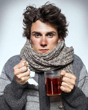 Man Cold Ill young man with red nose, scarf, sneezing into handkerchief. Medication or drugs abuse, healthcare conceptの写真素材