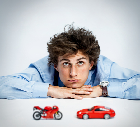 Contemplating young man thinking or dreaming about his future photos of young man resting his chin on his hands, laying on a table and looking upwards over gray backgroundの写真素材