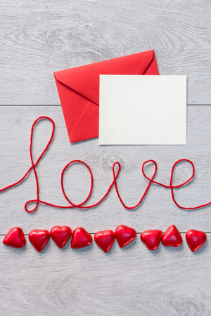 Word "love" and red envelope with letter on a wooden background. Valentines Day backgroundの写真素材