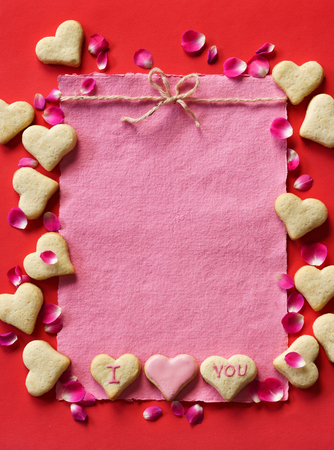 Heart shaped cookies for valentines day. Pink paper for text on red background. View from above.の写真素材