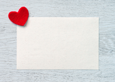 Valentines greeting card with a red heart and space for text on a wooden background.の写真素材