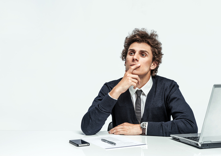 Pensive businessman looking up with concentration on grey background. Depression and crisis conceptの写真素材