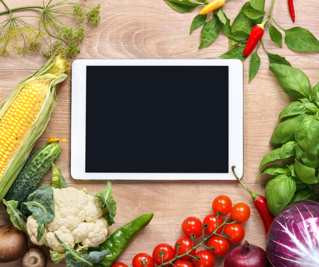 Purchase list. Space for text. studio photography of open blank ring bound notebook surrounded by a fresh vegetables on wooden tableの写真素材