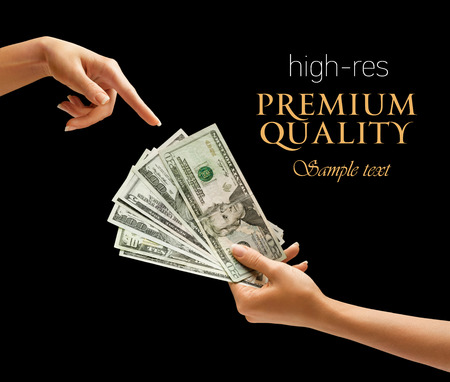 Hand holding dollars money and points finger at the money isolated on black backgroundの写真素材