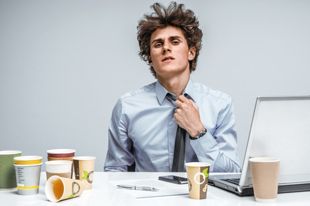 Tired student. Overwhelmed man turned away from the laptop screen. Education conceptの写真素材