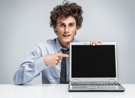 Young salesman showing at screen laptop / modern businessman at the workplace working with computerの写真素材