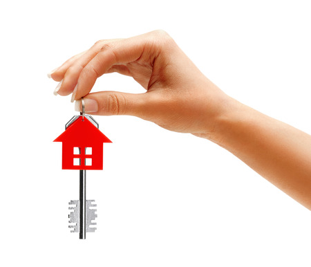 Woman's hand holding key to the apartment isolated on white backgroundの写真素材