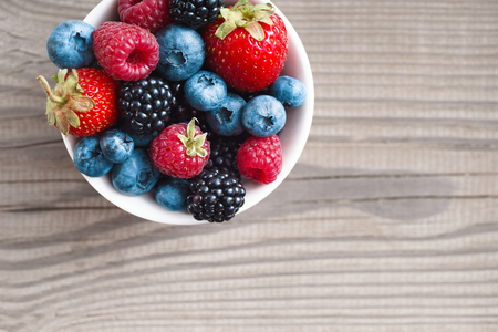 Mixed berries in plate on rustic wooden background. Close up, top view, high resolution product. Harvest Conceptの写真素材