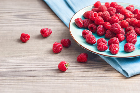Ceramic plate with raspberries at old wooden table. Close up, high resolution product. Harvest...