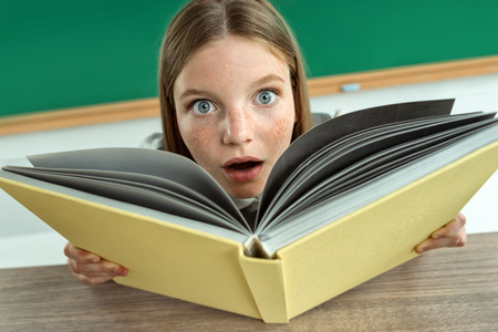 Astonished pupil staring at you with her mouth open. Photo of teen school girl, creative concept with Back to school themeの写真素材