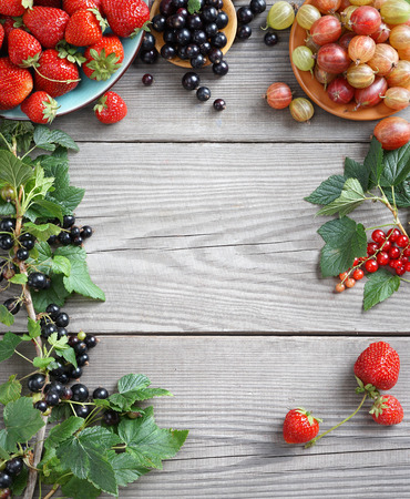 Frame from gooseberry, strawberry and branches with currants on wooden background. Close up, top view, high resolution product.の写真素材