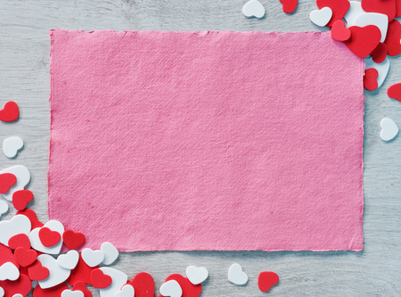 Pink paper on wooden table among decorative red and white hearts. Copy space for your text. Valentines Day conceptの写真素材